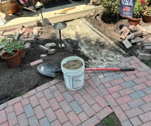 A residential walkway in progress with pavers and tools laid out for use